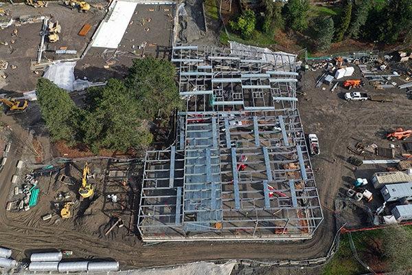 aerial view of structural steel framing being installed on a concrete pad for a large buidling