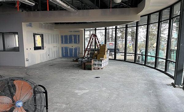 an interior room under construction with a curved wall of windows